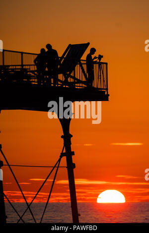 Aberystwyth Wales UK, Mittwoch, 25. Juli 2018 UK Wetter: die Menschen werden durch den herrlichen Sonnenuntergang über Aberystwyth Pier Silhouette am Ende eines Tages des heißen Sommer Sonnenschein. Großbritannien große Hitzewelle fort, mit wenig Erholung von der sehr trockenen Wetter trotz etwas Regen in der Prognose für das Wochenende Foto: Keith Morris/Alamy leben Nachrichten Stockfoto