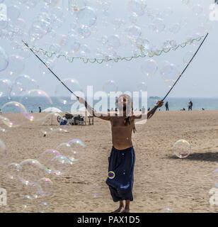 Barcelona, Spanien - 8. Mai 2018: Mann, der eine Menge Seifenblasen auf den Strand Barceloneta in sonniger Tag. Strand Barceloneta in bunte Seifenblasen. Stockfoto