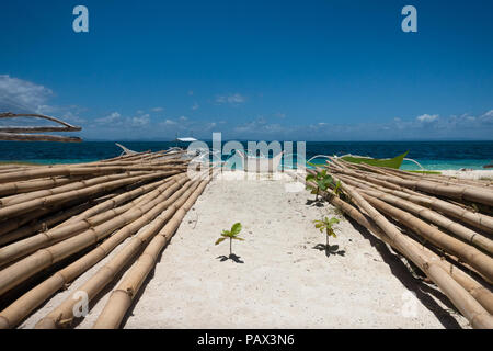 Stapel von großer Bambusstangen in der Nähe von traditionellen Fischerboote an einem tropischen Strand in Cebu, Philippinen Stockfoto