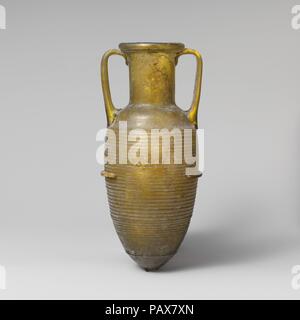 Glas Amphore (jar). Kultur: Roman. Abmessungen: 8 5/8 in. (21,9 cm) Durchmesser: 3 cm. (8,9 cm) Breite (Griffe): 3 7/8 in. (9,8 cm). Termin: Anfang 1. Jh. N.CHR.. Durchsichtig gelb grün; Griffe in der gleichen Farbe auch röhrenförmige Rim, gefaltet und im; breit, zylindrische Hals; konvexe Wölbung der Schulter; länglich eiförmigen Körper verjüngt sich bis zu einem Punkt; zwei Griffe wie Pads auf der Schulter, ausgearbeitet und leicht heraus, dann horizontal gedreht und gedrückt am Nacken und an der Unterseite der Kante nach oben. 30 - Vier eng horizontalen Rippen, die von der Schulter zum unteren Körper, dann ein einfaches Band bef Stockfoto