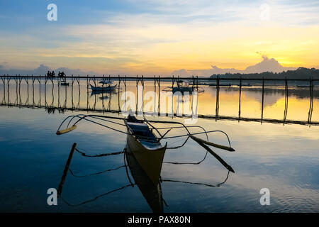 Die philippinischen Insel Fischerboote durch hölzerne Pier angedockten, mit Sonnenuntergang Reflexion im Meer - Siargao, Philippinen Stockfoto