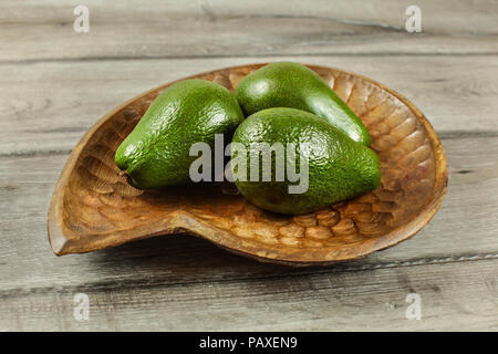 Drei ganze avocado Birnen in Houten, auf rustikalen Tisch. Stockfoto