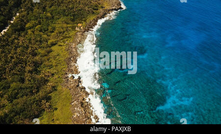 Die Küstenlinie der tropischen Insel Siargao mit Regenwald auf einem Hintergrund von Meer mit großen Wellen. Luftbild: Meer mit Felsen, den Strand und die Wellen. Philippinen. Travel Concept. Stockfoto