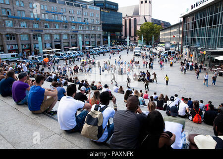 Leute sitzen auf der Treppe bilden die Cathedral Square zum Hauptbahnhof und hören Straßenmusikern, Köln, Deutschland. Menschen Artikel in der Tre Stockfoto