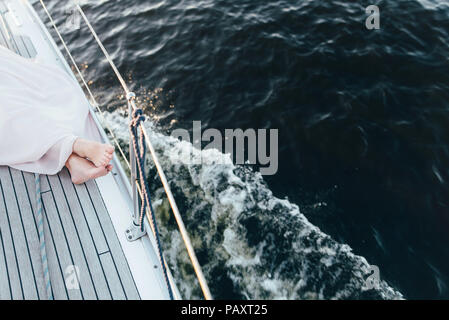 Die Beine einer Frau liegend auf einer Yacht aufliegt und auf dem Hintergrund der Behälter. Stockfoto