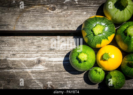 Mini zucchini Kugel Kugel acht gelbe und grüne über Holz Tisch Curcurbita pepo Flach Stockfoto