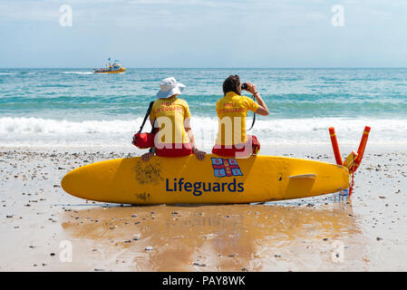 Unter einem blauen Sommerhimmel die Damen der Tenby RNLI Lifeguards wache über Urlauber auf Schloss Strand im hübschen Küstenort Tenby. Stockfoto