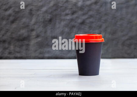 Schwarzes Papier Tasse Kaffee auf hölzernen Tisch Stockfoto