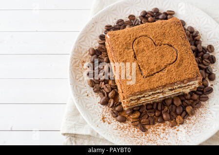 Köstliches Tiramisu Kuchen mit Kaffee Bohnen auf einem Schild auf einem hellen Hintergrund. Stockfoto