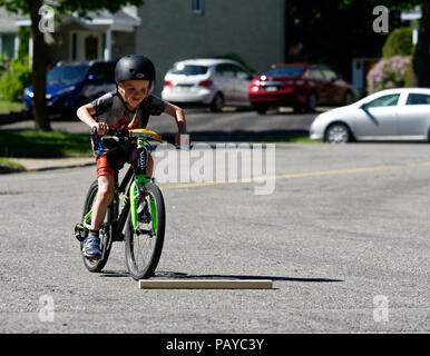 Ein Junge (6 Jahre alt) Sprüngen in der Straße auf seinem Fahrrad Stockfoto