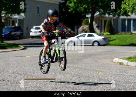 Ein Junge (6 Jahre alt) Sprüngen in der Straße auf seinem Fahrrad Stockfoto