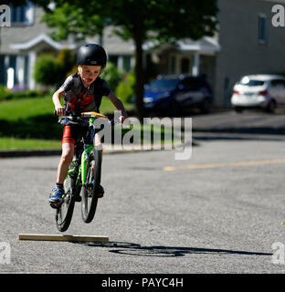 Ein Junge (6 Jahre alt) Sprüngen in der Straße auf seinem Fahrrad Stockfoto