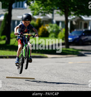 Ein Junge (6 Jahre alt) Sprüngen in der Straße auf seinem Fahrrad Stockfoto