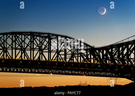 Der Pont du Quebec und der St. Lawrence River in der Dämmerung vom Parc de la Marina de La Chaudière, St-Romuald mit einer sichelförmigen Mond mit erdschein hinter Stockfoto