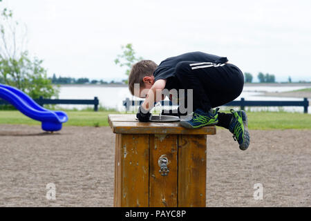 Ein Junge (6 Jahre alt), die auf den Brunnen geklettert ist zu trinken Stockfoto