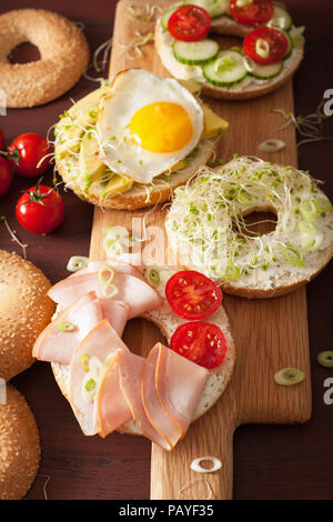 Auswahl an Sandwiches auf Bagels: Ei, Avocado, Schinken, Tomate, Weichkäse, Alfalfa Sprossen Stockfoto