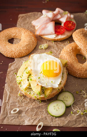 Auswahl an Sandwiches auf Bagels: Ei, Avocado, Schinken, Tomate, Weichkäse, Alfalfa Sprossen Stockfoto