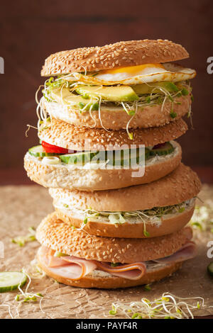 Auswahl an Sandwiches auf Bagels: Ei, Avocado, Schinken, Tomate, Weichkäse, Alfalfa Sprossen Stockfoto