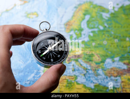 Kompass in der Hand auf dem Hintergrund einer Karte der Welt Nahaufnahme Stockfoto