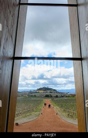 Blick auf die Stadt Laguardia in Spanien von einer hölzernen Fenster in der Weinverkostung Zimmer mit Menschen, die durch die rote Piste und Weinberge an. Stockfoto