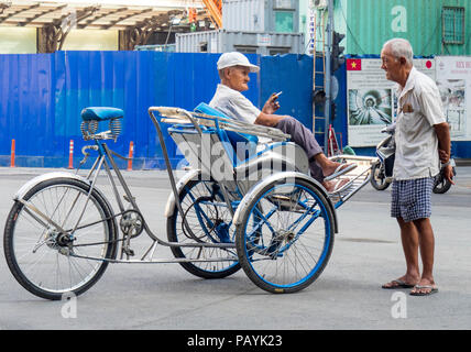 Zwei ältere Vietnamesische Männer, eine Sitzung auf einem Dreirad oder rikscha ein Gespräch, Ho Chi Minh City, Vietnam. Stockfoto