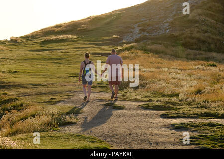 Ein Paar mittleren Alters Hand und gemeinsam zu Fuß auf der South West Coast Path in der Nähe von Newquay in Cornwall. Stockfoto