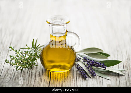 Olivenöl mit frischen Kräutern auf hölzernen Hintergrund Stockfoto
