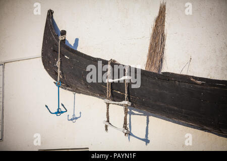 Eine alte verlassene Holz- Boot auf einer Wand angezeigt. Stockfoto