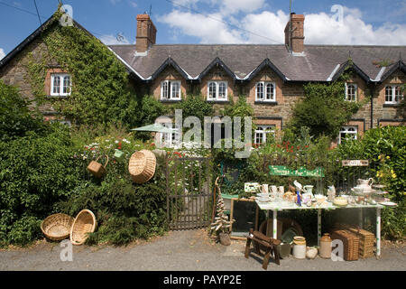 Cottage mit üppigen Garten im Rhos mit Artikel zum Verkauf auf einem Tisch am Straßenrand Stockfoto