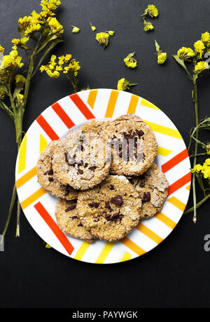 Haferflocken Kekse mit Schokolade auf einem Teller mit leuchtend gelben Blumen Stockfoto