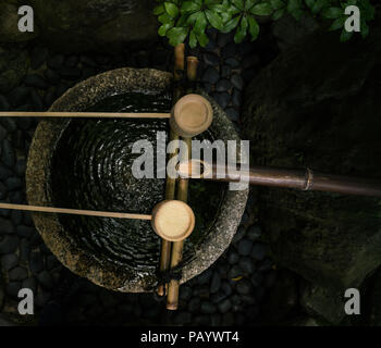 Tsukubai (蹲踞) oder ein Waschbecken am Eingang des Soihoji, Kokedera moss Garden in Kyoto. Besucher reinigen Wasser, bevor sie eintreten. Stockfoto