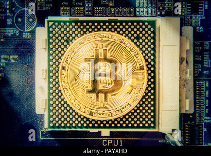 Eine große goldene physischen Bitcoin (digitale virtuelle crypto-Währung) Austausch einer CPU auf einem Motherboard. Stockfoto