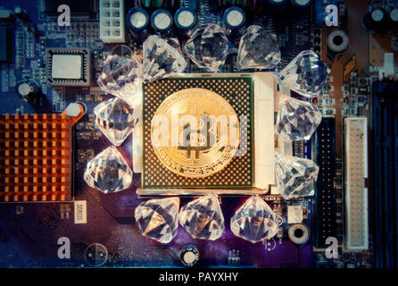 Eine große goldene physischen Bitcoin (digitale virtuelle crypto-Währung) Austausch einer CPU auf einem Motherboard, von glänzenden Diamanten umgeben. Stockfoto