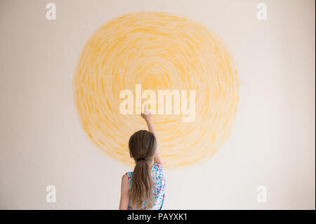 Kleines Mädchen Zeigefinger am gelben Sonne auf Wand innen lackiert Stockfoto