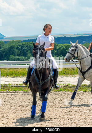 PYATIGORSK, Russland - Juli 22, 2018: Schöne Frauen zeigen Elemente der Winkelzug, reiten ein braunes Pferd auf der Pferderennbahn Pyatigorsk. Stockfoto