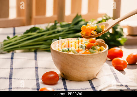 Schöpfkelle aus gedämpftem frisch geernteten jungen Gemüse, einschließlich Crinkle cut geschnittene Karotten, Erbsen und Kartoffeln für eine gesunde Begleitung zum Abendessen Stockfoto