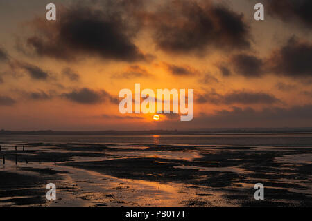 Flaming orange Sonnenuntergang von Seasalter Strand genommen, Whitstable an der Nord Küste von Kent in der Swale Estuary, UK. Stockfoto