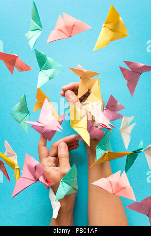 Psychische Gesundheit Konzept. Bunte Papier Schmetterlinge fliegen und sitzen auf womans Hände. Harmonie Emotion. Origami. Papier schneiden Stil. Stockfoto