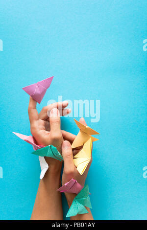 Psychische Gesundheit Konzept. Bunte Papier Schmetterlinge fliegen und sitzen auf womans Hände. Harmonie Emotion. Origami. Papier schneiden Stil. Stockfoto