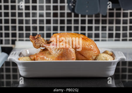 Ganz heißen Ofen gekocht gebratenes Huhn. Vorbereitet Sonntag Mahlzeit mit Kartoffeln auf der Küchenarbeitsplatte für Carving und dienen zum Abendessen bereit. Stockfoto