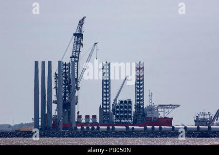 Offshore-windparks Bau. Investitionen in Erneuerbare saubere Energie als Versorgungsschiff Schiff angedockt ist und bereit, wind turbine Teile zu erhalten. Stockfoto