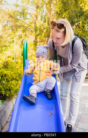 Mutter und Sohn fahren die Rutsche auf dem Spielplatz Stockfoto