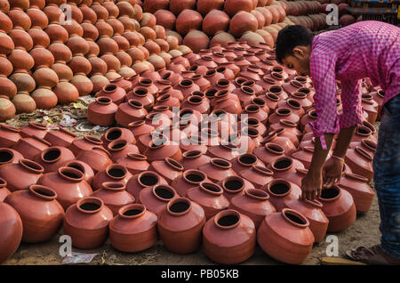AHMEDABAD, Indien - Dezember 10, 2017: Unbekannter potter Anordnen von Terracotta Ton Wasser Töpfe in der Nähe seines Hauses. Lehm Töpfe sind seit der Antike verwendet. Stockfoto