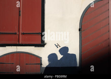 Schatten von ein paar Liebhaber an einer Wand eines alten Hauses aus der Sonne mit geschlossenen Jalousien