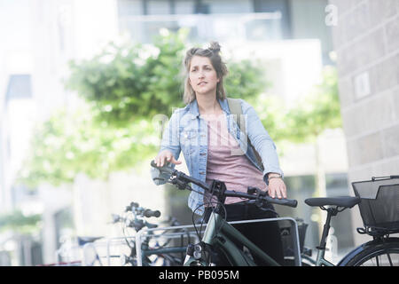 Frau, die neben einem Fahrrad Stockfoto