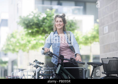 Lächelnde Frau neben einem Fahrrad stehend Stockfoto