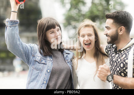 Drei Freunde mit ihren Armen um jede andere Musik hören Stockfoto
