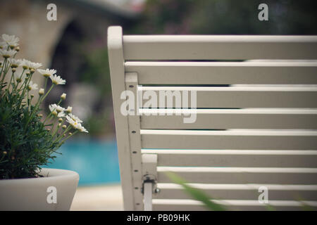 Holz Stuhl neben einem Blumentopf mit Gänseblümchen Stockfoto