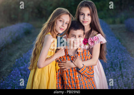 Drei lächelnde Kinder stehen in einem Lavendelfeld, Schipka, Stara Zagora, Bulgarien Stockfoto