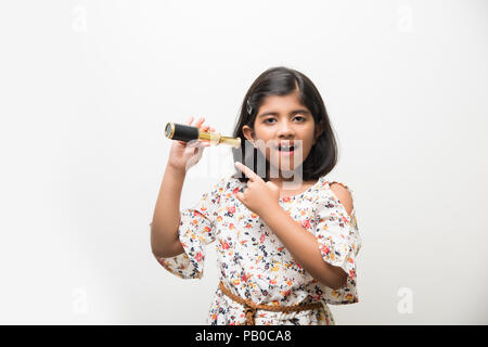 Nette kleine indische / asiatische Mädchen mit Stretch-Teleskop und Blick in den Himmel, wollen ein Wissenschaftler sein. Isoliert stehend über weißem oder grünem Chalkbo Stockfoto